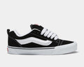 Vans Knu Skool Core sneakers in black suede with white side stripe, thick white laces, and vulcanized outsole, side view.