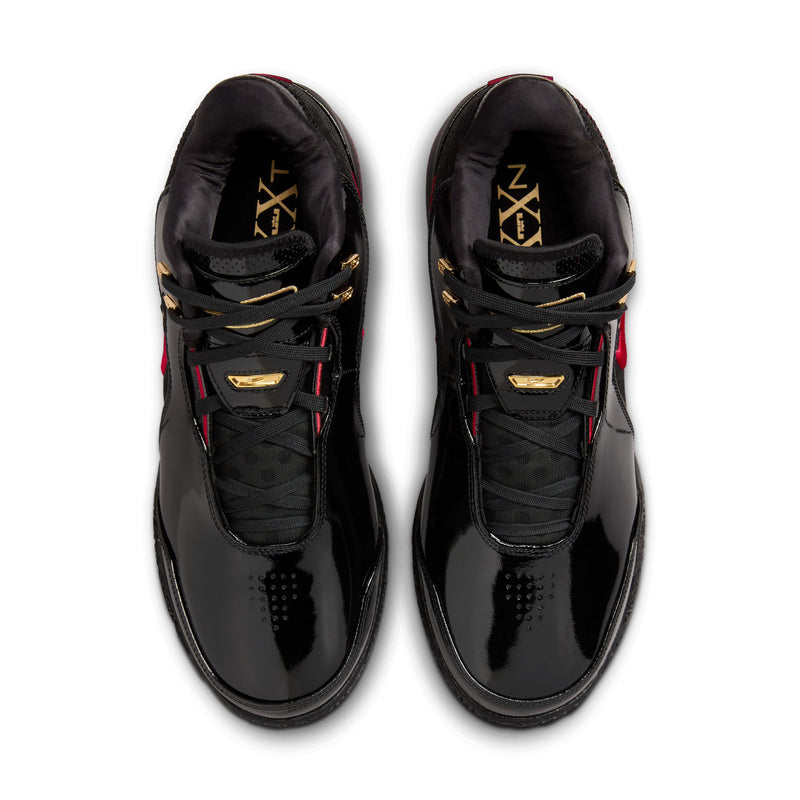 Nike LeBron NXXT Gen AMPD basketball shoes in black with red and gold accents, glossy finish and perforated toe box, top view.