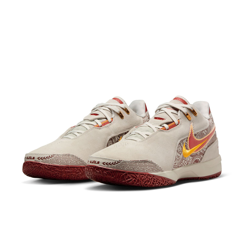 Nike LeBron NXXT Gen AMPD basketball shoes in beige with red and gold accents, suede upper, and patterned red outsole, front angle view.