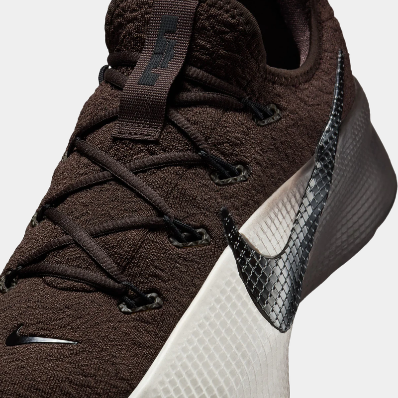 Brown athletic shoe with black and white accents on a light gray background