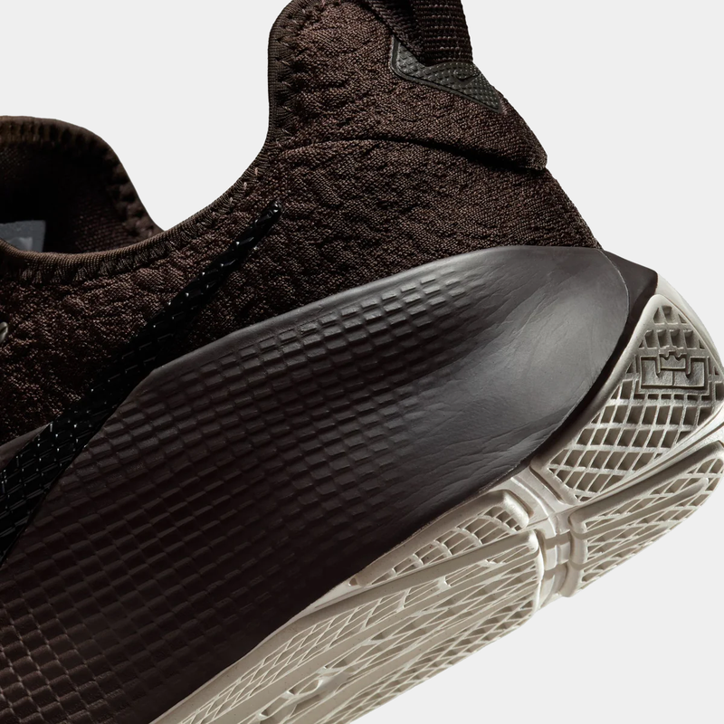 Close-up of a black sneaker with a textured sole on a light gray background