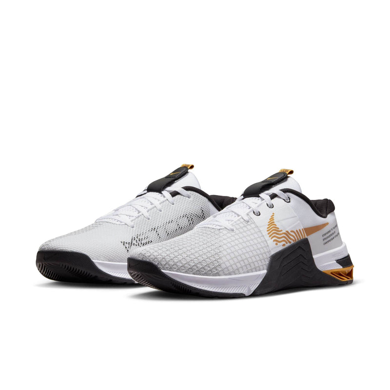 Nike Metcon 8 training shoes in white with gold accents, breathable mesh upper, and durable black outsole, front angled view.