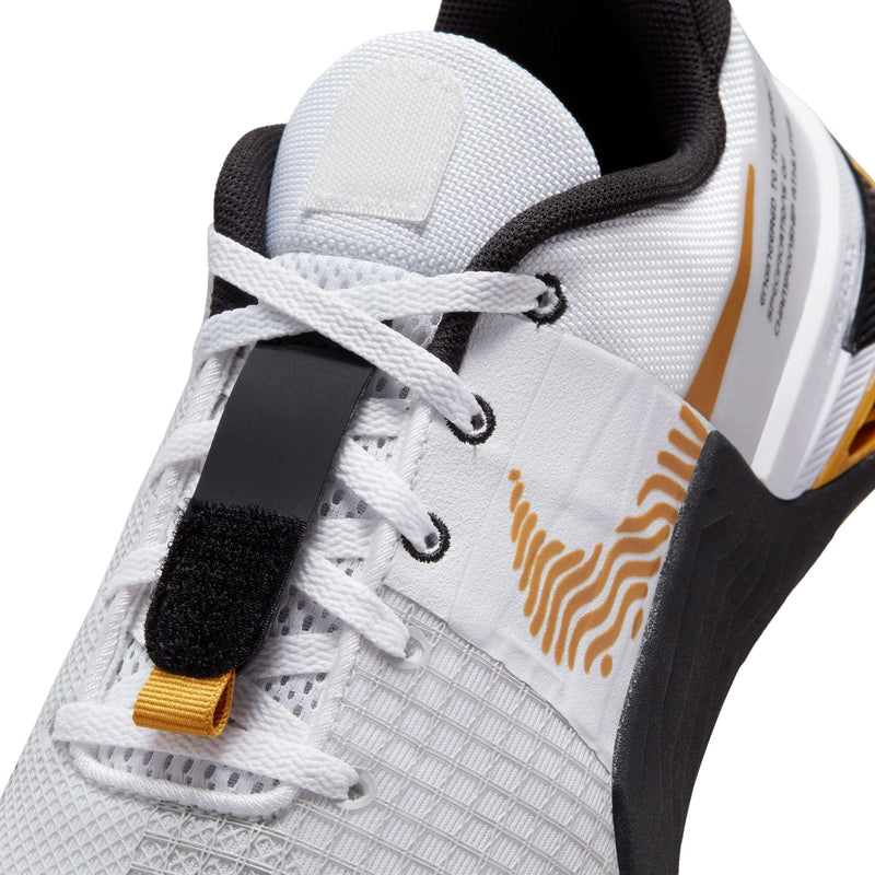 Nike Metcon 8 training shoes close-up showing breathable white mesh upper, lace system, and gold and black design accents.