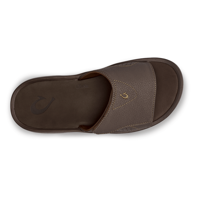 OluKai Nalu Slide sandals in brown with textured strap, gold logo detail, and cushioned footbed, top view.