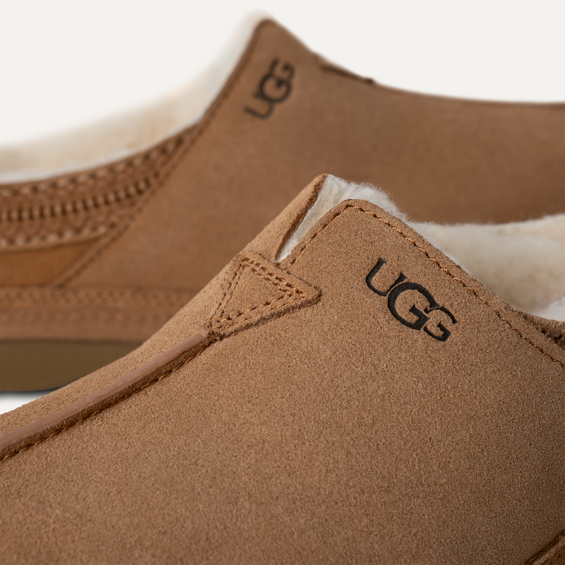 UGG Neuman slippers in chestnut suede with plush sheepskin lining and stitched detailing, close-up side view.