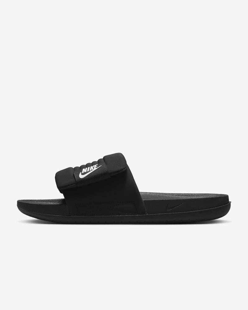 Nike Offcourt Adjustable Slide sandals in black with padded strap, white logo detailing, and textured foam sole, side view.