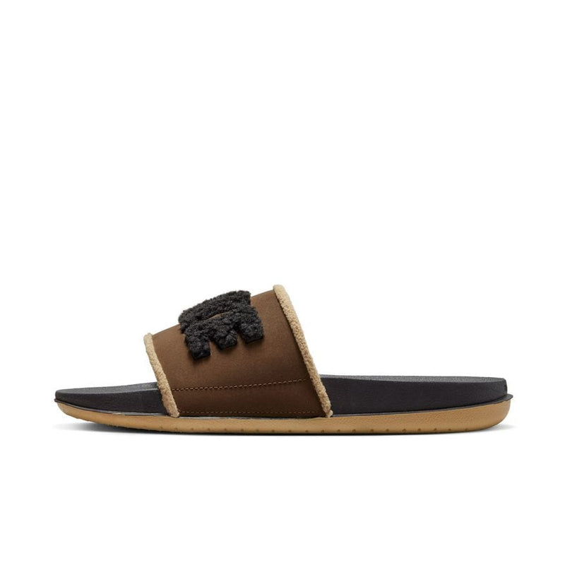 Nike Offcourt Slide SE slides in brown with cozy fleece-lined strap and textured Nike logo, side view showing cushioned sole.
