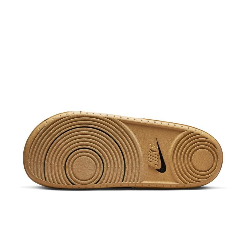 Nike Offcourt Slide SE sandal outsole in tan rubber with circular traction pattern and embossed Nike logo, bottom view.