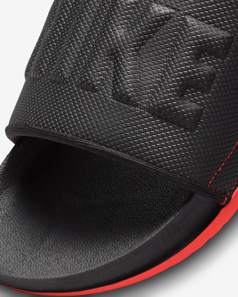 Nike Offcourt Slide sandals in black with textured upper, embossed logo, and red sole accents, close-up of toe area.