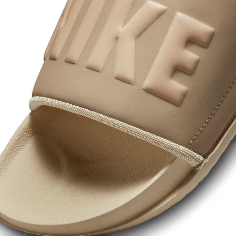 Nike Offcourt Slide sandals in beige with embossed Nike branding on soft synthetic strap and textured footbed, close-up view.