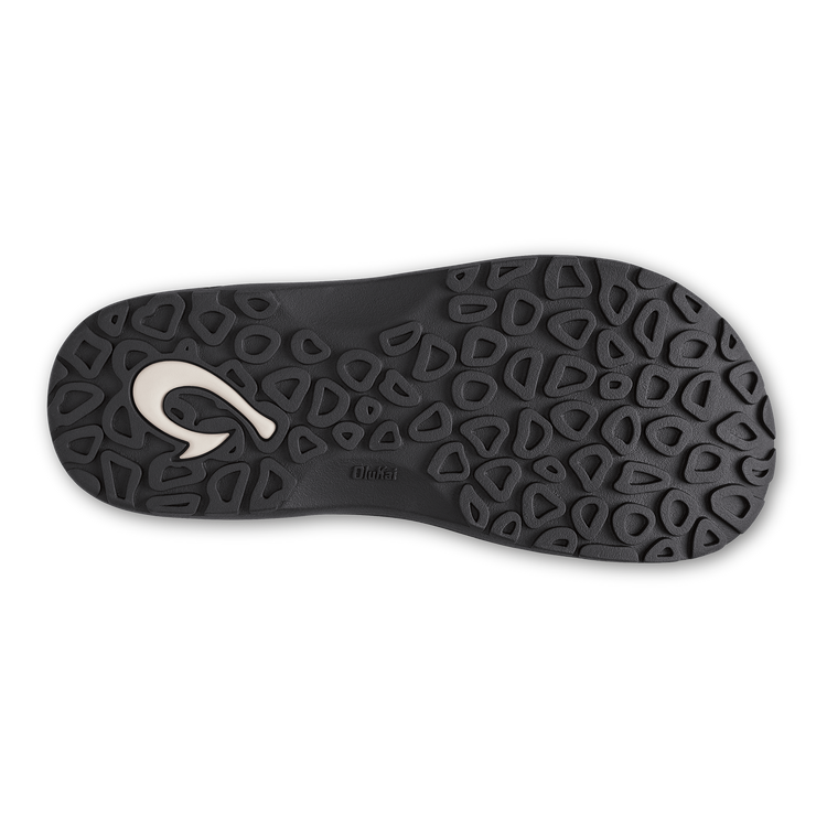OluKai ‘Ohana sandal outsole in black rubber with textured grip pattern and logo detailing, sole/bottom view.