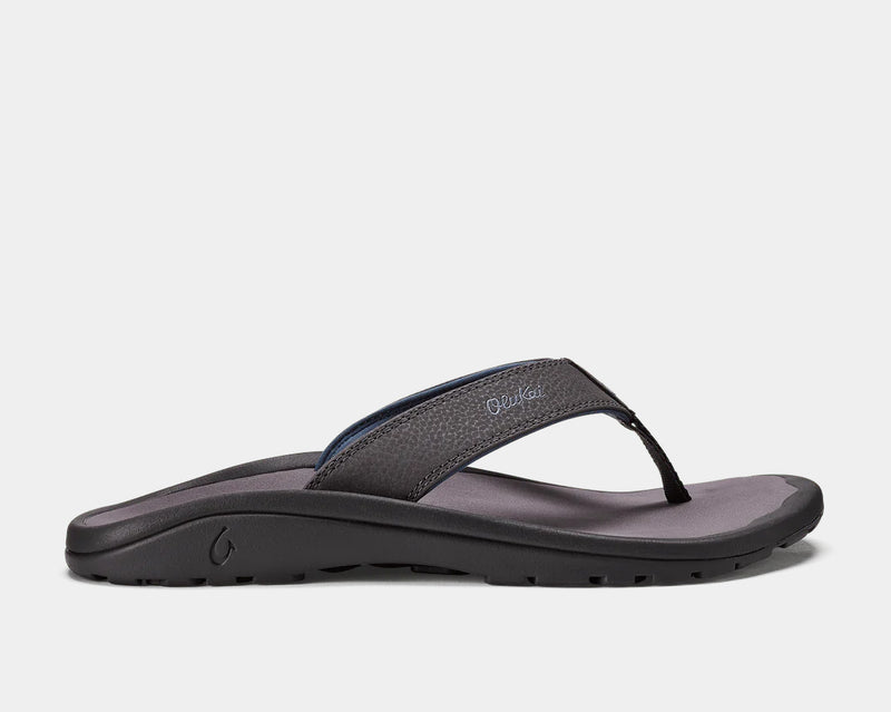 OluKai Ohana sandals in black with a textured synthetic strap and cushioned footbed, side view.