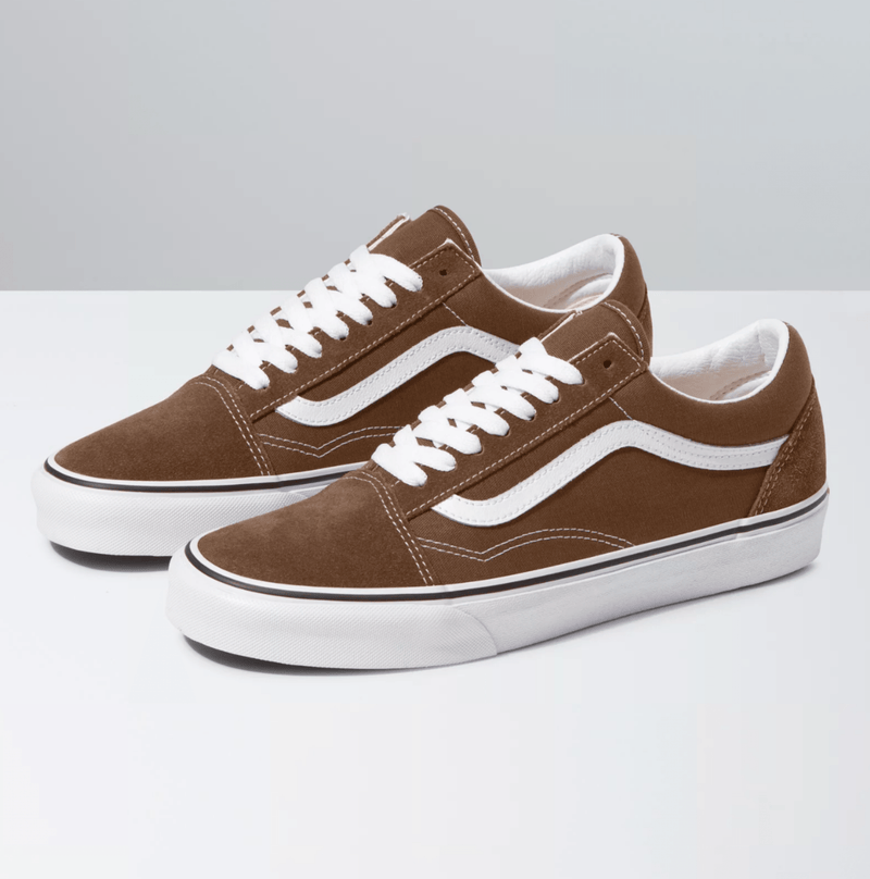 Vans Old Skool sneakers in brown suede with white leather side stripe, white laces, and a rubber waffle outsole, side/front angle.