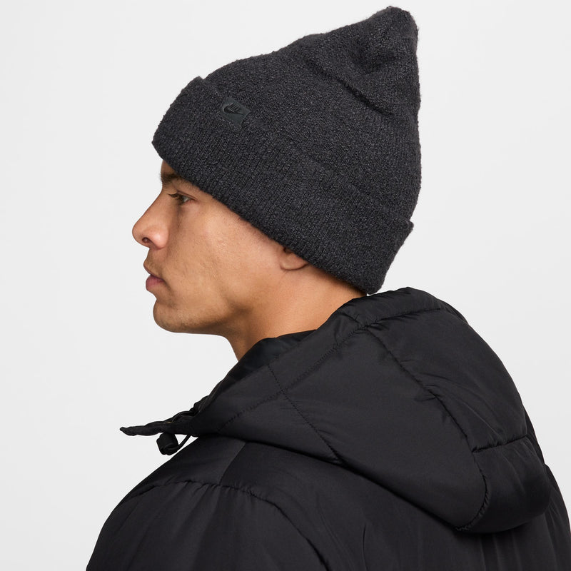 Nike Peak beanie in dark gray knit fabric with subtle Nike logo, side view.