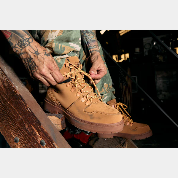 DC WorkCrew Peary TR Work Waterproof Comp Toe Boot in tan leather with durable laces and rugged outsole, worn by worker on wooden stairs.
