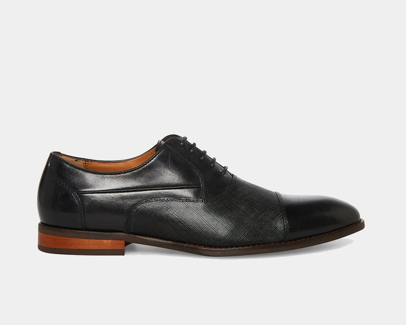 Steve Madden Proctor dress shoes in black leather with textured detailing, almond toe cap, and wooden sole, side view