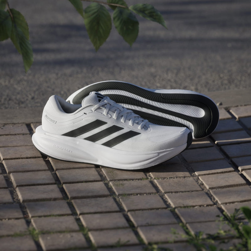 Adidas Response 2 running shoes in white with black stripes, featuring a Cloudfoam midsole, side view displayed outdoors.