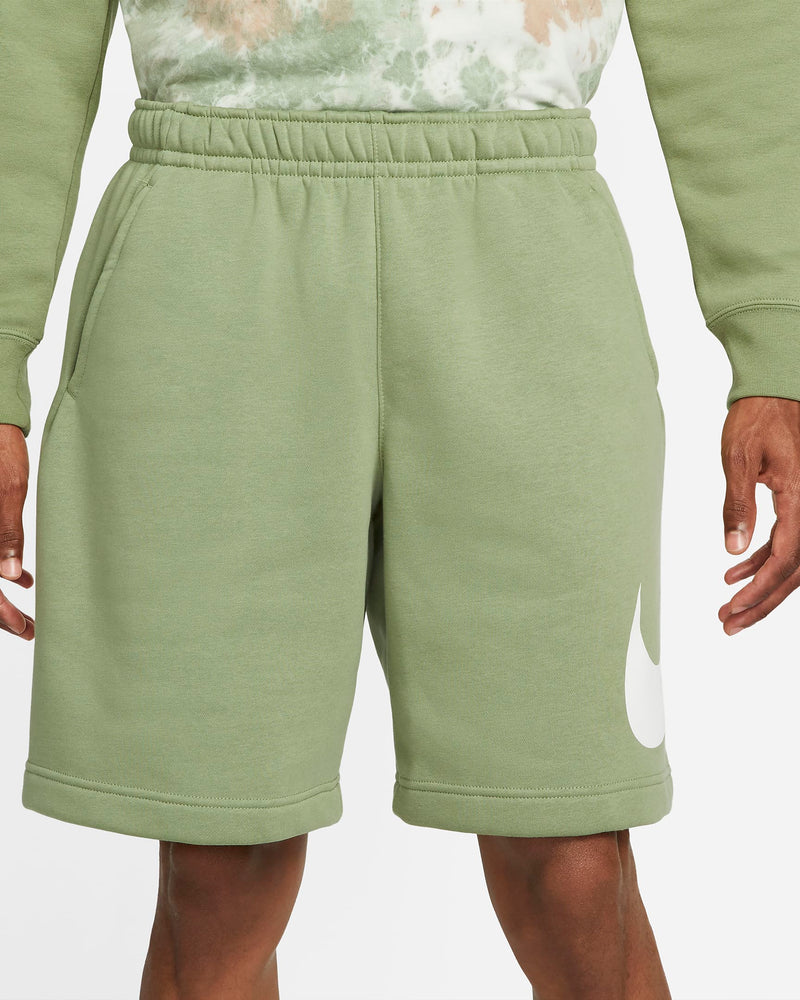 Nike Sportswear Club Shorts in light green with elastic waistband, relaxed fit, and white Nike Swoosh logo, front view.