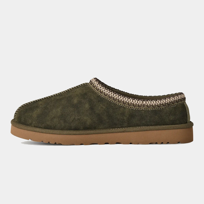 UGG Tasman Baxter suede slip-on shoes in olive green with braided collar detail and brown outsole, side view.