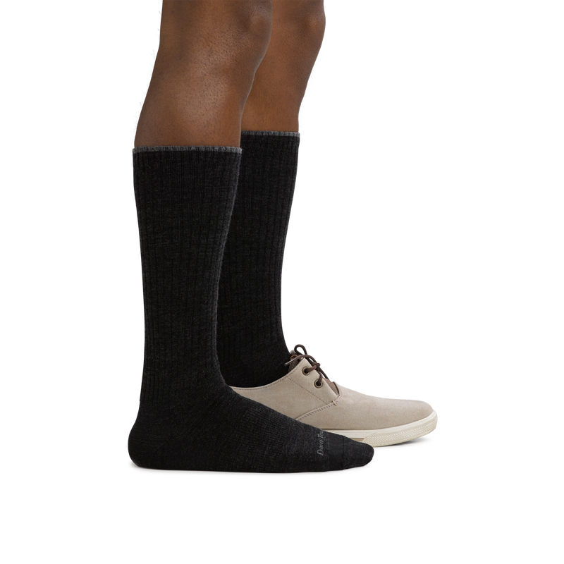 Darn Tough The Standard Mid-Calf Lightweight Lifestyle Socks in black with a ribbed texture, worn with beige shoes, side view.