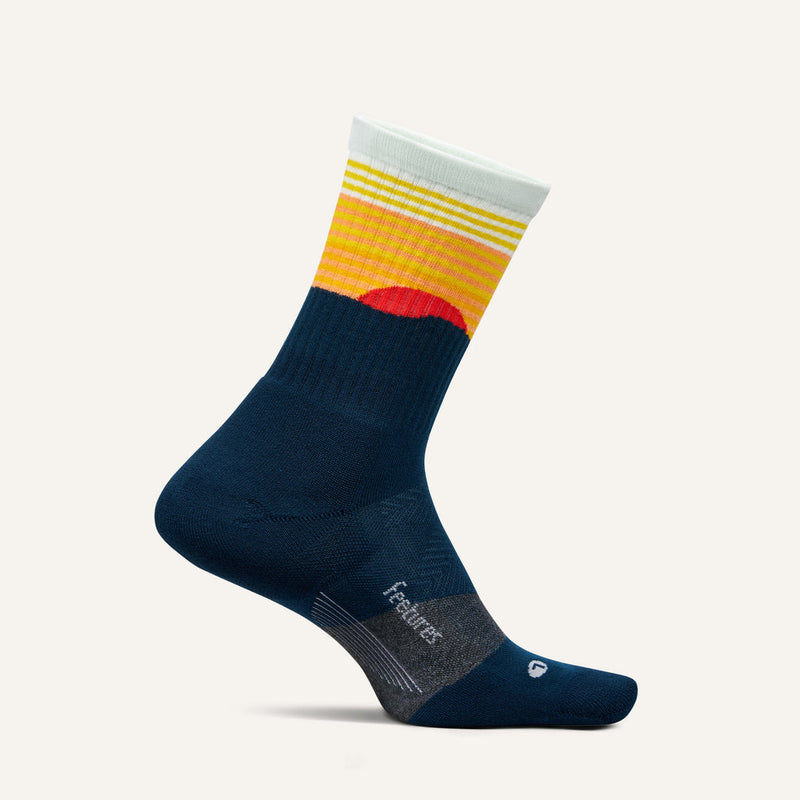 Feetures Trail Max Cushion Mini Crew Sock in navy blue with orange, yellow, and white gradient pattern, side view.