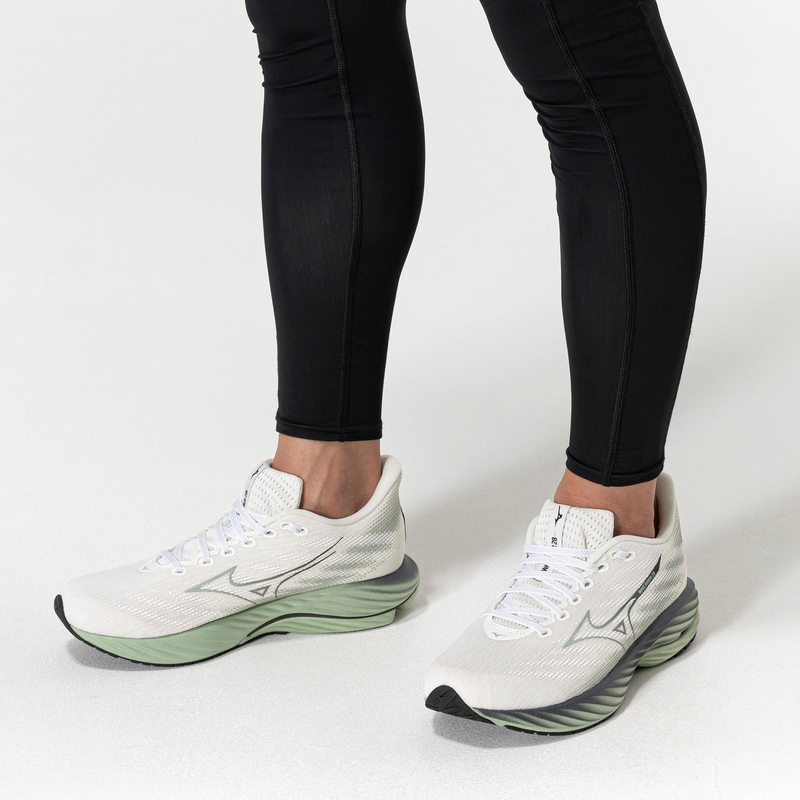 Mizuno Wave Rider 29 running shoes in white with mesh upper, wave-styled green midsoles, and black outsole, worn by runner.