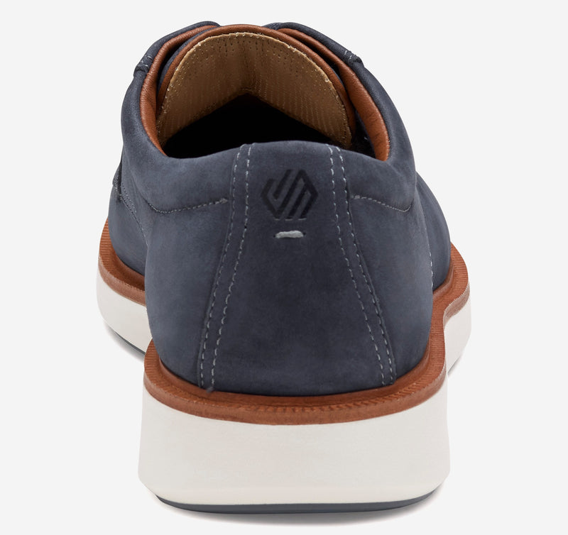Johnston & Murphy XC+ Parker shoes in navy blue suede with tan accents and white outsole, back view.